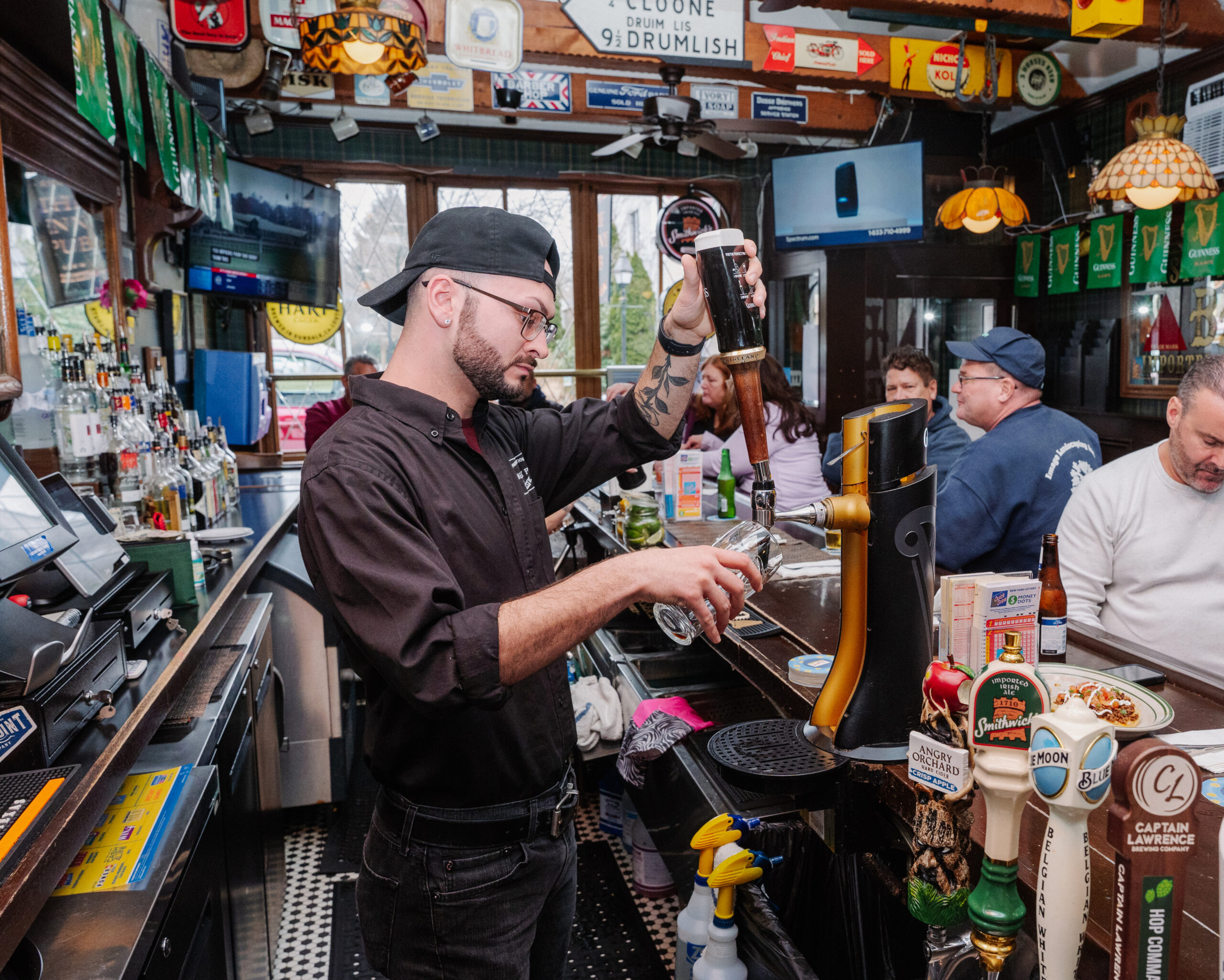 A bartender pouring a Guinness at Shoregate Apartments in Bay Shore, featuring people sitting at the bar.