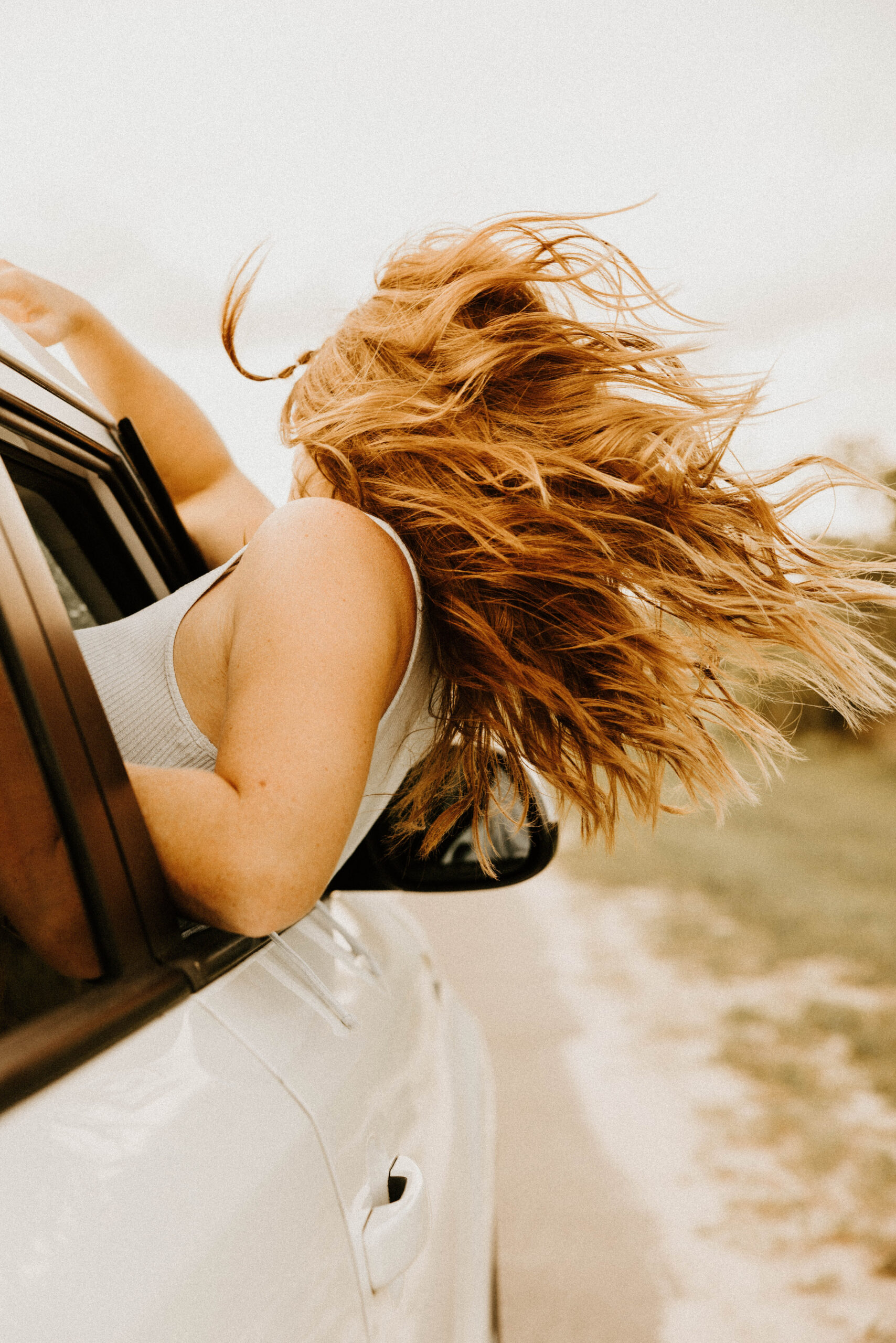 Someone leaning out of the window of a car near Shoregate Apartments in Bay Shore, with her hair blowing in the wind.